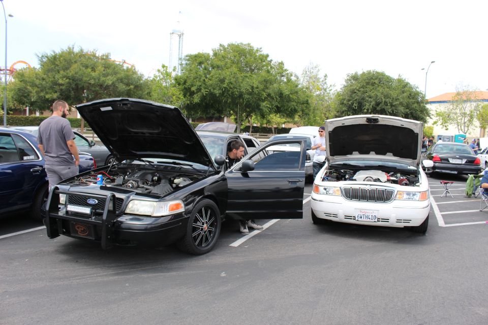 Black Ford Crown Victoria with push bar beside a white Lincoln, hoods up