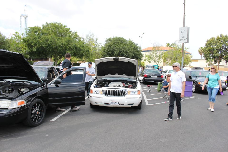 White Mercury Grand Marquis with hood up at a car show, people nearby