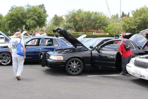 Black Ford Crown Victoria, doors and hood open, people viewing it