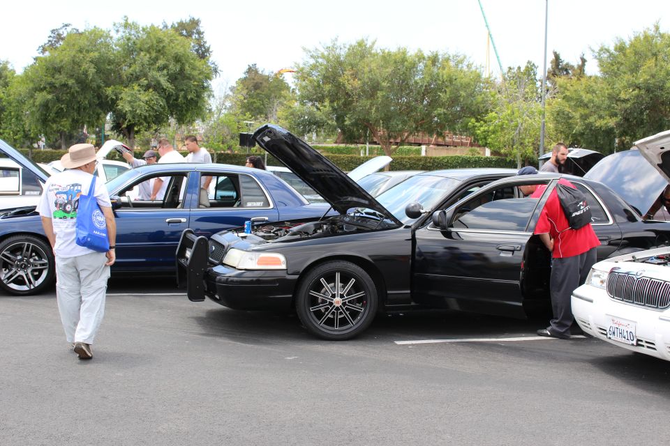 Black Ford Crown Victoria, doors and hood open, people viewing it