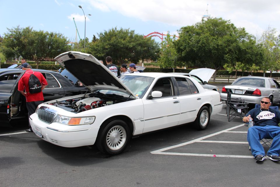 White Mercury Grand Marquis with hood up, man seated beside it