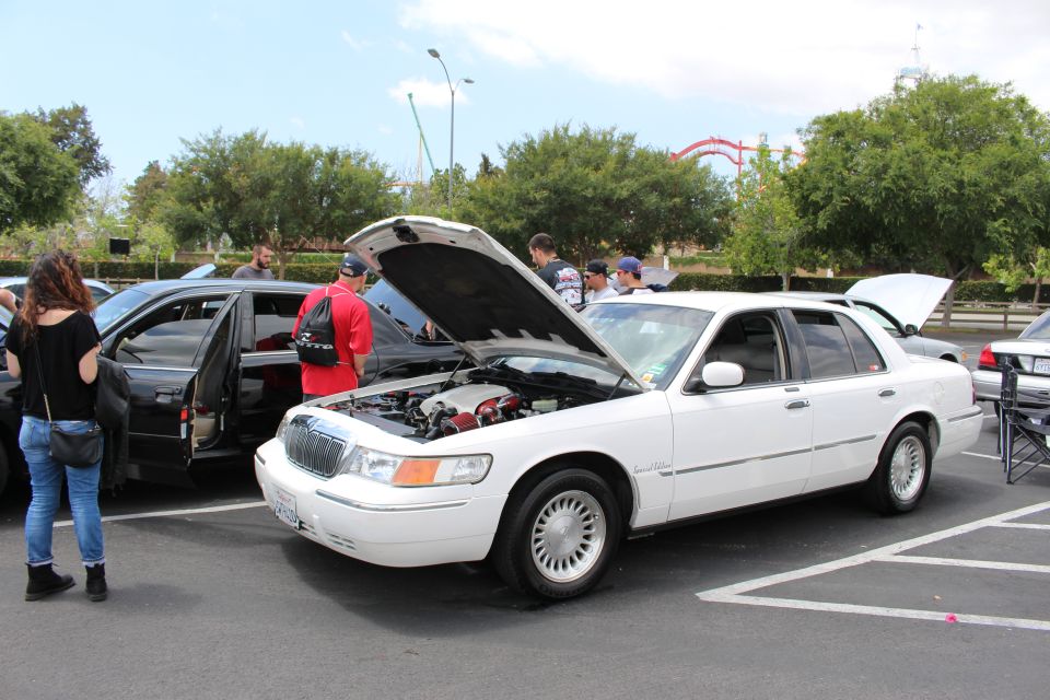 White Mercury Grand Marquis with hood up, attendees standing around