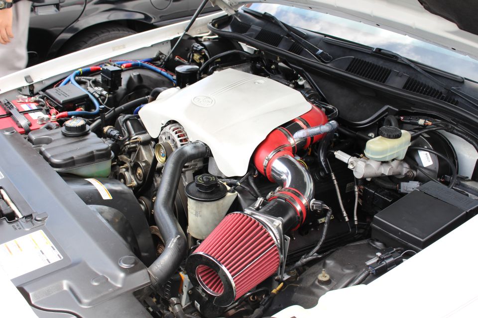 Detailed V8 engine bay of a white sedan with red cone intake filter
