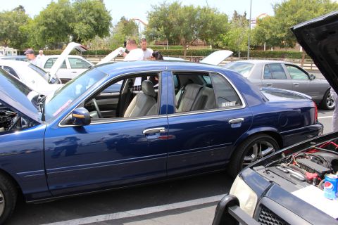 Side profile of a blue Ford full-size sedan with a Police Interceptor decal at a car show