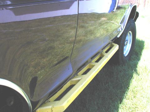 1979 Ford Bronco - Side view of a dark SUV prominent yellow step bars.