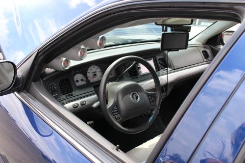 Interior of a Mercury sedan with steering wheel, gauge cluster, A-pillar pod gauges and dash-mounted screen