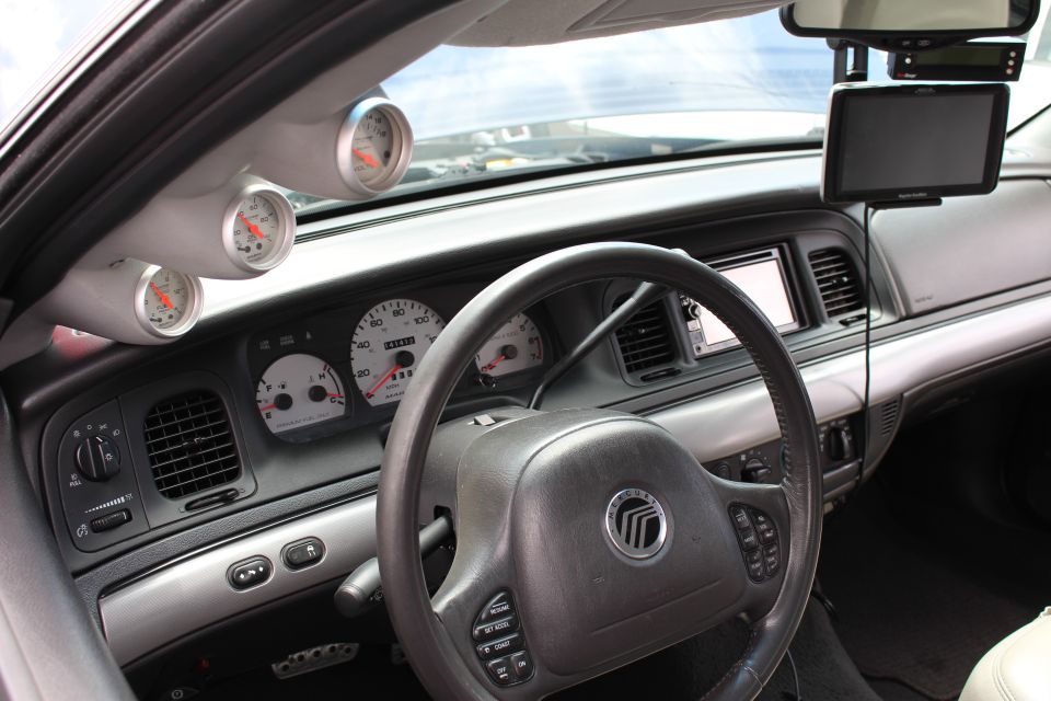 Mercury sedan dashboard and steering wheel with A-pillar gauge pod and navigation screen