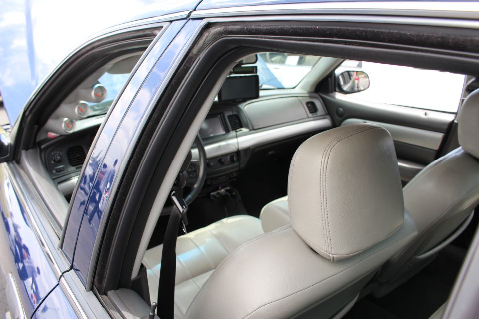 Rear window view into a blue sedan showing gray leather seats, headrest and dashboard