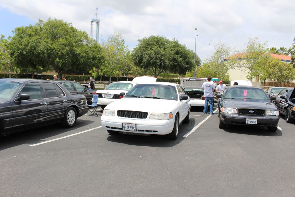 White Ford Crown Victoria with WHITE VIC plate between black and gray Crown Victorias at a show
