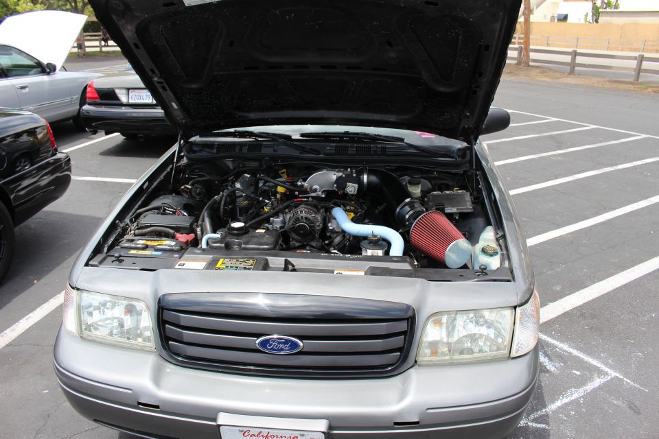 Engine bay of a silver-gray Ford sedan with red cone air intake