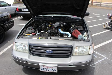 Front engine bay view of a gray Ford sedan with red air filter, hood open