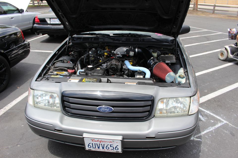 Front engine bay view of a gray Ford sedan with red air filter, hood open