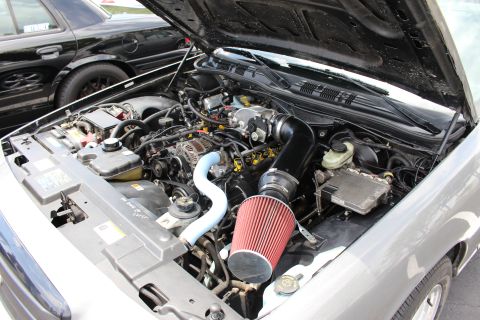 Modified V8 engine bay with red cone air filter in a silver car
