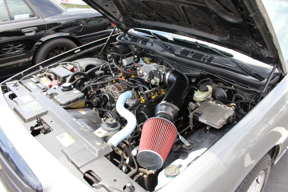 Modified V8 engine bay with red cone air filter in a silver car