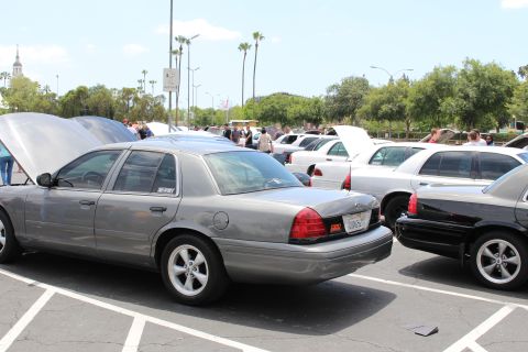 Rear three-quarter view of a gray Ford sedan at a parking-lot car show