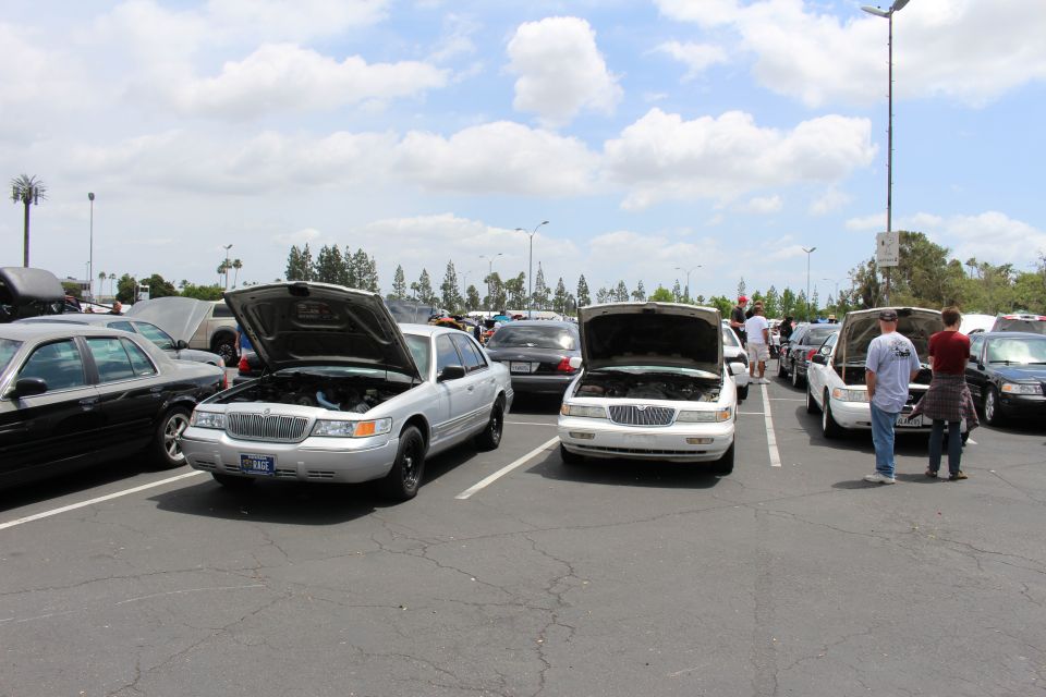 Silver Mercury and Lincoln sedans with hoods up at a car meet