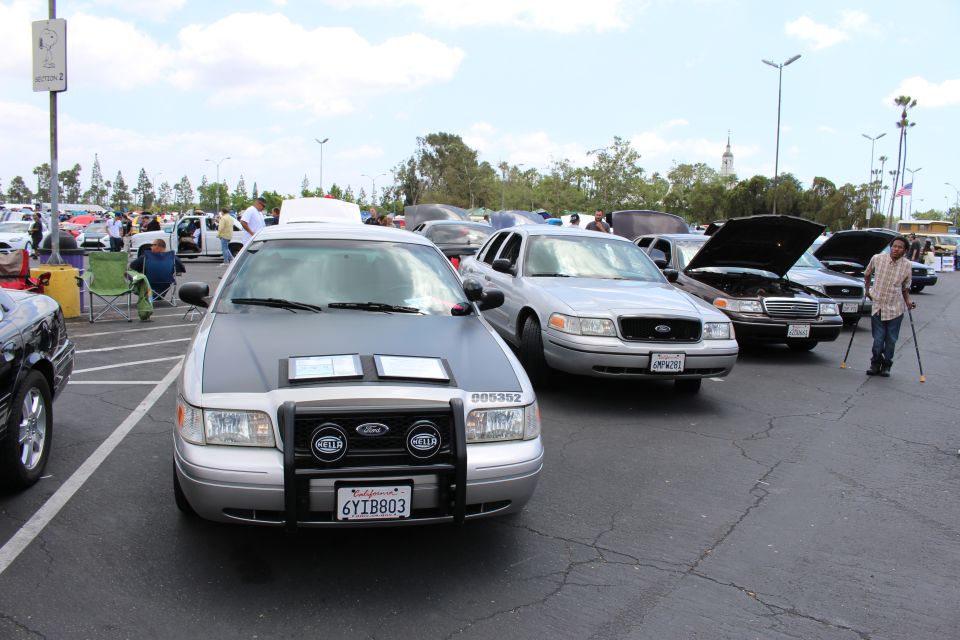 Silver Ford sedan with push bar and HELLA lights facing camera among parked cars