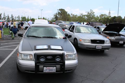 Front of a silver Ford sedan with push bar beside another silver Ford sedan at a meet