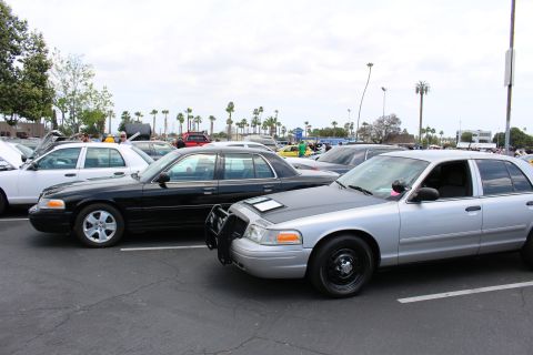 Silver and black full-size sedans parked nose-to-tail under a cloudy sky at a car meet