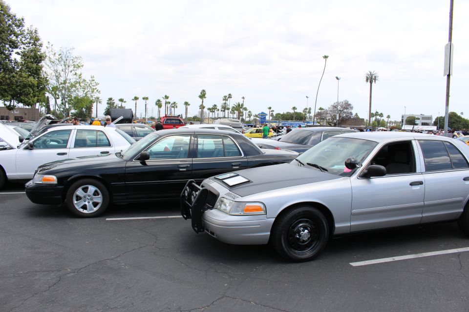 Silver and black full-size sedans parked nose-to-tail under a cloudy sky at a car meet