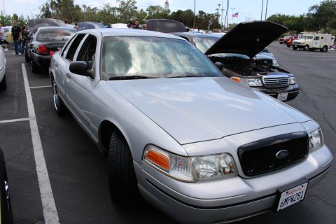 Silver Ford sedan with blacked-out grille parked at an angle at a car meet