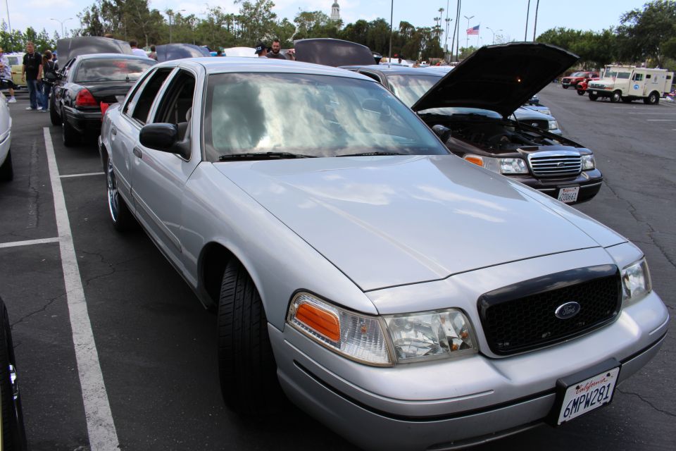 Silver Ford sedan with blacked-out grille parked at an angle at a car meet