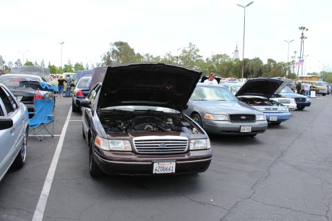 Dark maroon Ford sedan with raised hood beside a silver Ford sedan at a car meet