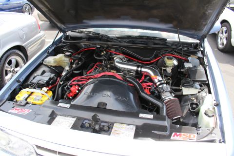 Engine bay with red plug wires, polished intake tube and Caution Fan shroud