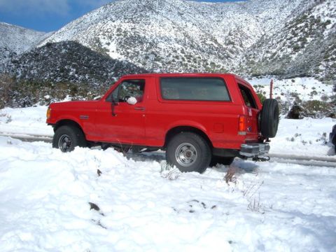 1988 Ford Bronco - Red 1988 Ford Bronco navigating a snowy mountain road.