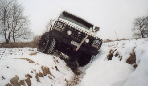 1980 Ford Bronco - A white Ford Bronco navigates a challenging snowy terrain, demonstrating its off-road capabilities.