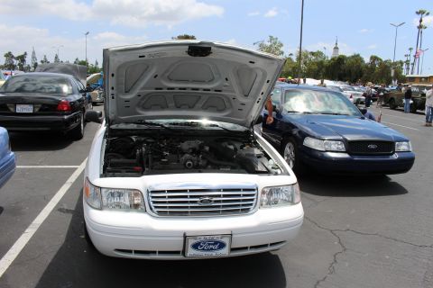 White Ford Crown Victoria with hood up viewed from the front at a car show