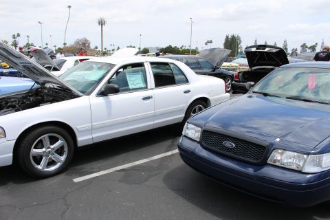 White Crown Victoria beside a dark blue Ford sedan in a car-show lot