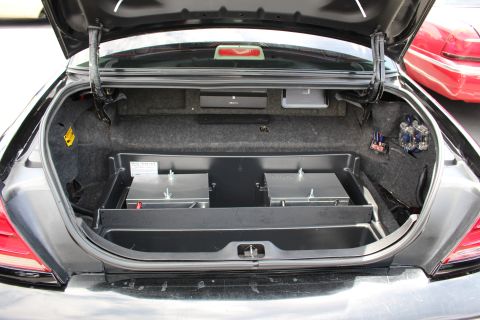 Open trunk of a dark sedan showing carpeted floor and storage tray