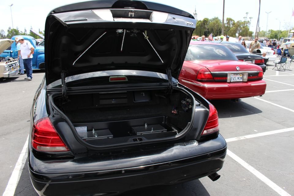 Black sedan with open trunk beside a red Grand Marquis at a car meet