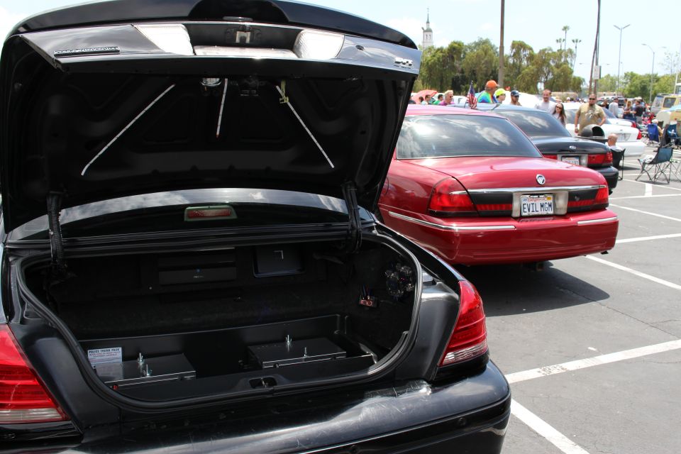 Open trunk of a black sedan with a red Grand Marquis parked alongside