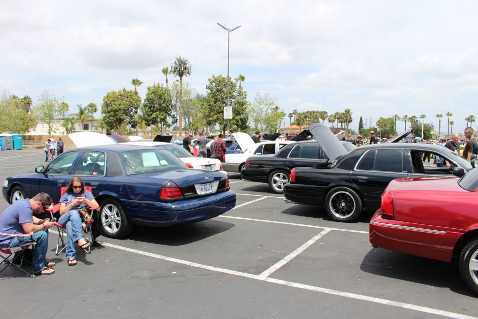 Dark blue and black sedans at a car meet with people seated in chairs