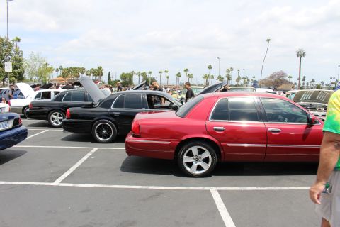 Red Mercury Grand Marquis and black sedan parked at an outdoor car meet