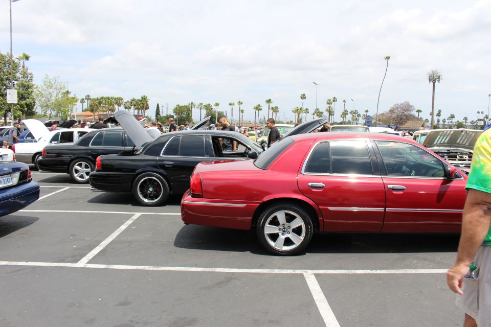 Red Mercury Grand Marquis and black sedan parked at an outdoor car meet