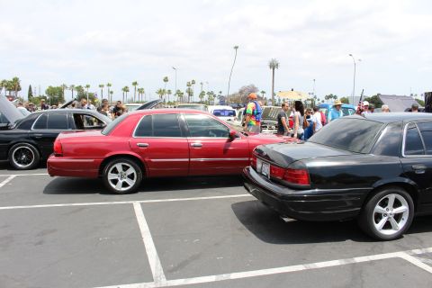 Red full-size sedan parked nose-to-nose with a black sedan at an outdoor car show