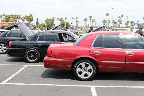 Black and maroon full-size sedans parked side by side at a car show