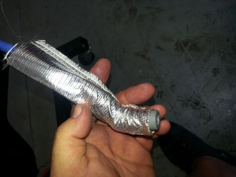 1994 Ford Bronco - A close-up shows a hose covered in reflective heat shielding, held in a person's hand.