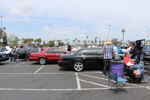 Red and black full-size sedans parked among a car show crowd