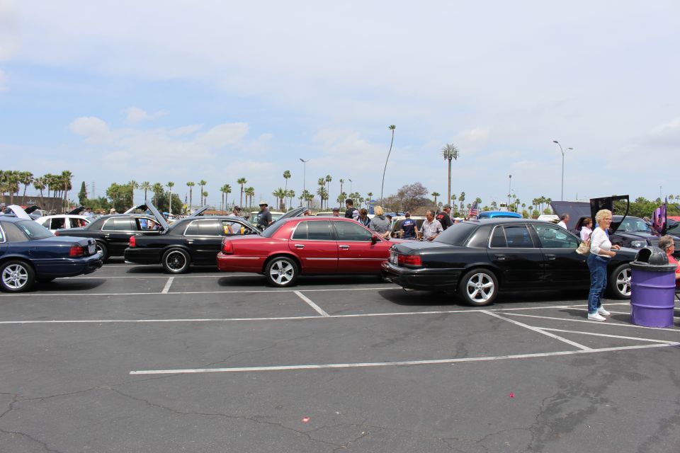 Row of dark and red full-size sedans parked at a car show