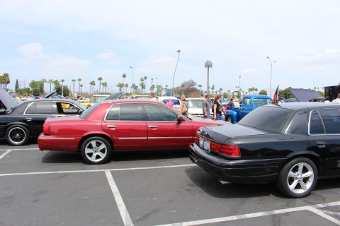 Maroon and black full-size sedans parked nose-to-tail at a car show