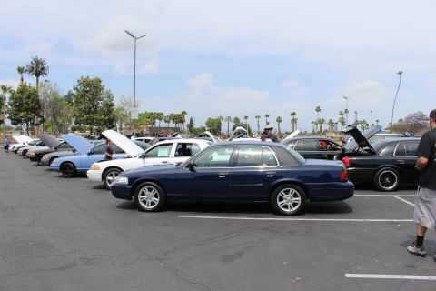 Dark blue full-size sedan parked among a row of show cars