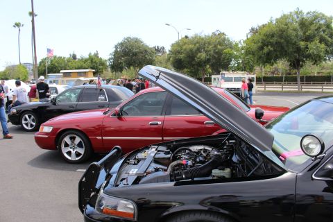 Black sedan with raised hood showing engine beside a red sedan