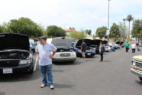 Man in white shirt standing by Mercury sedans with open hoods