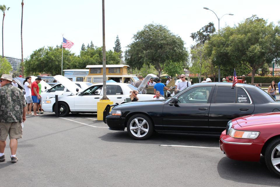 Black sedan parked beside a white police-style sedan and flag