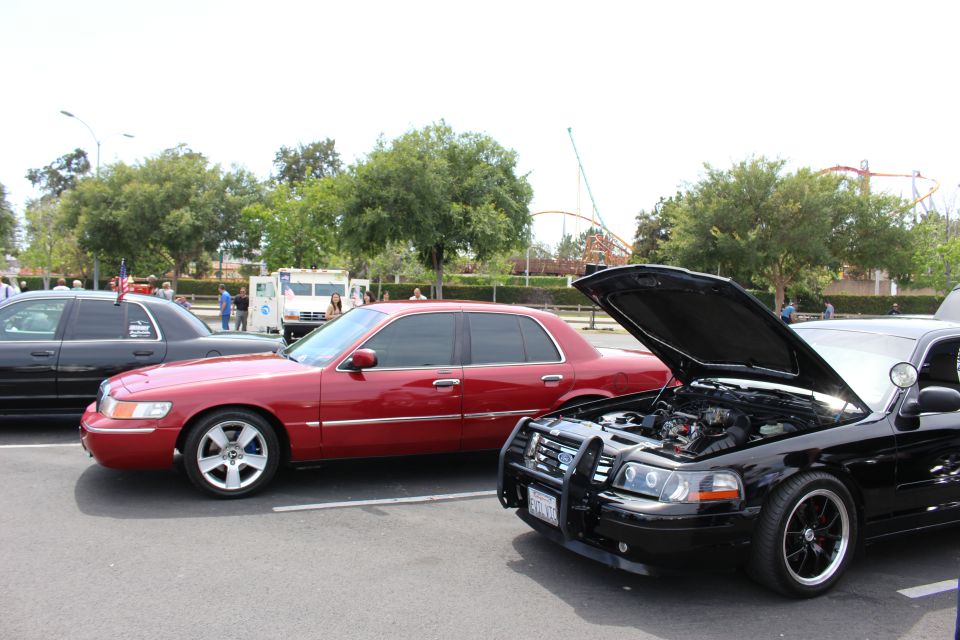 Red sedan and black sedan with open hood near an amusement park