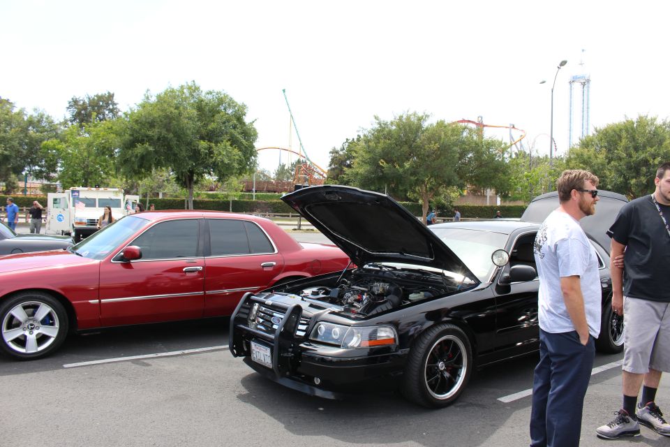 Black Ford sedan with open hood, men watching, coaster in background